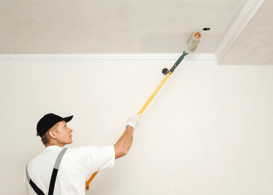 Professional painter painting a ceiling with long brush.