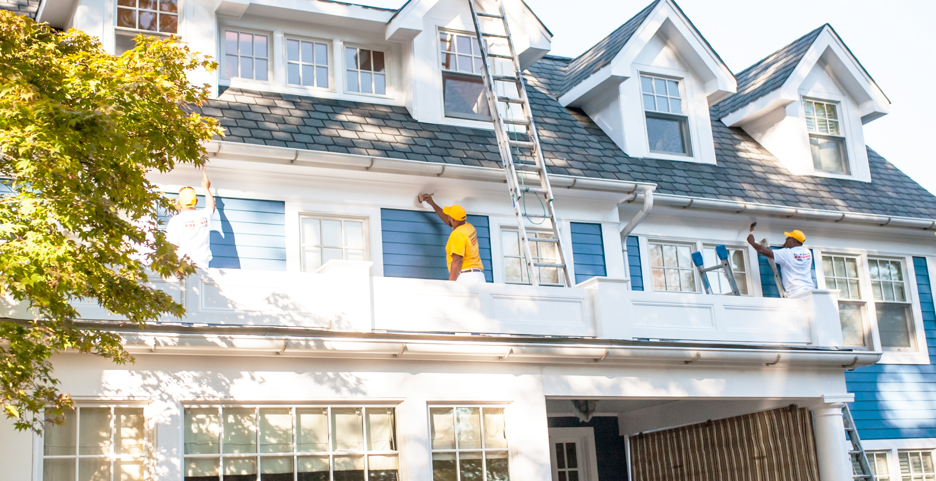 Painting professionals working on the outside exterior of a house