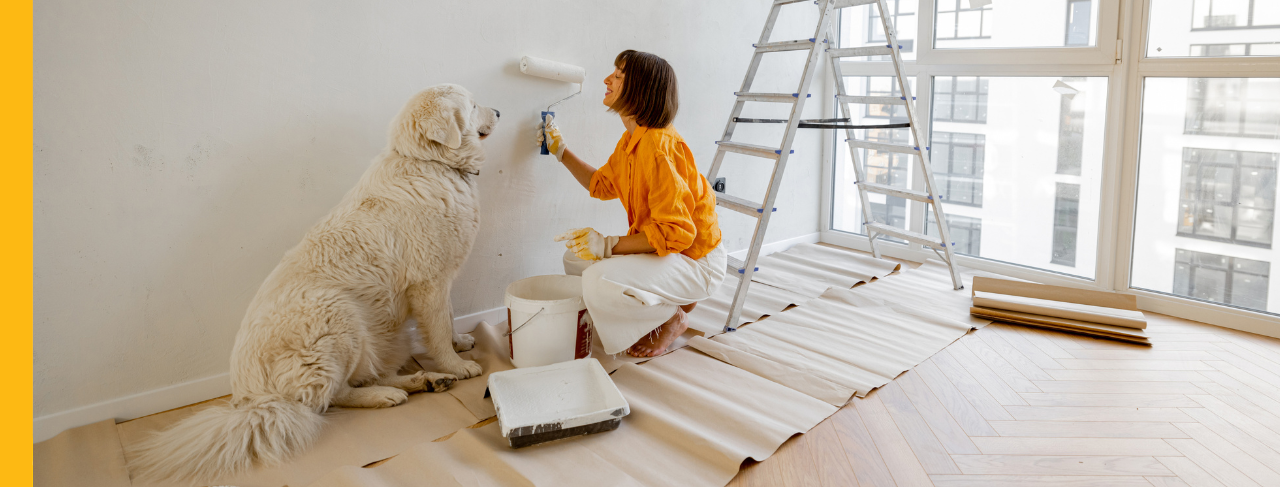 woman painting wall of home with dog