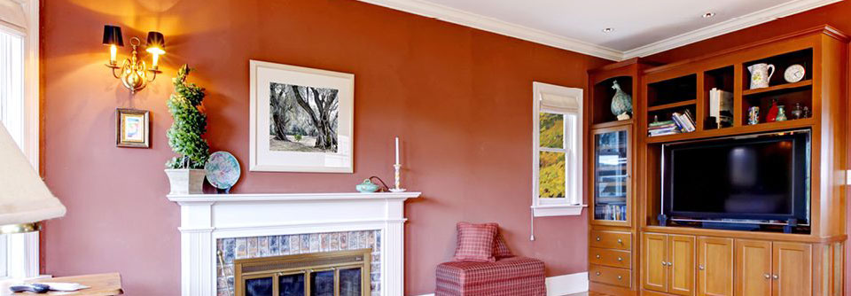 Residential family room with a large entertainment center and TV on the right and a fireplace in the middle of the room painted in Cavern Clay by Sherwin Williams