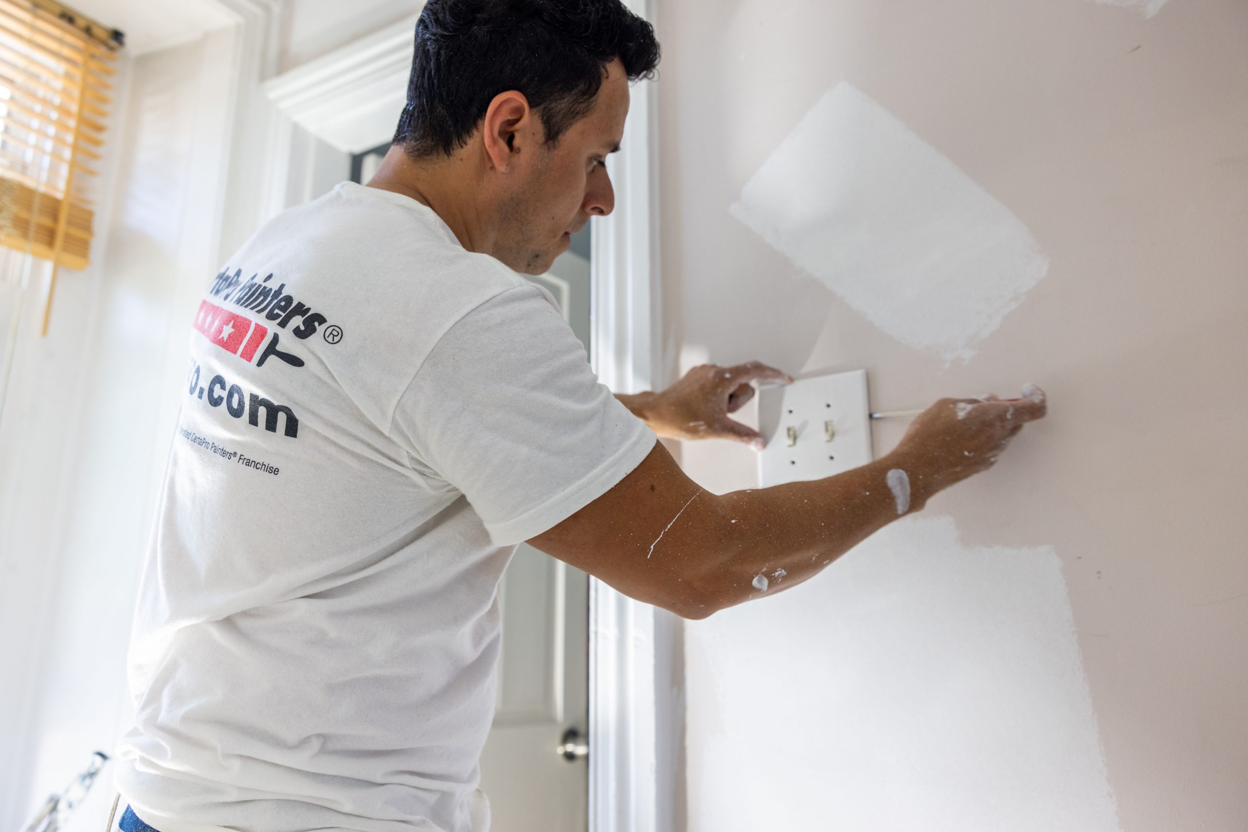 A CertaPro Painters painter preparing an interior wall surface.