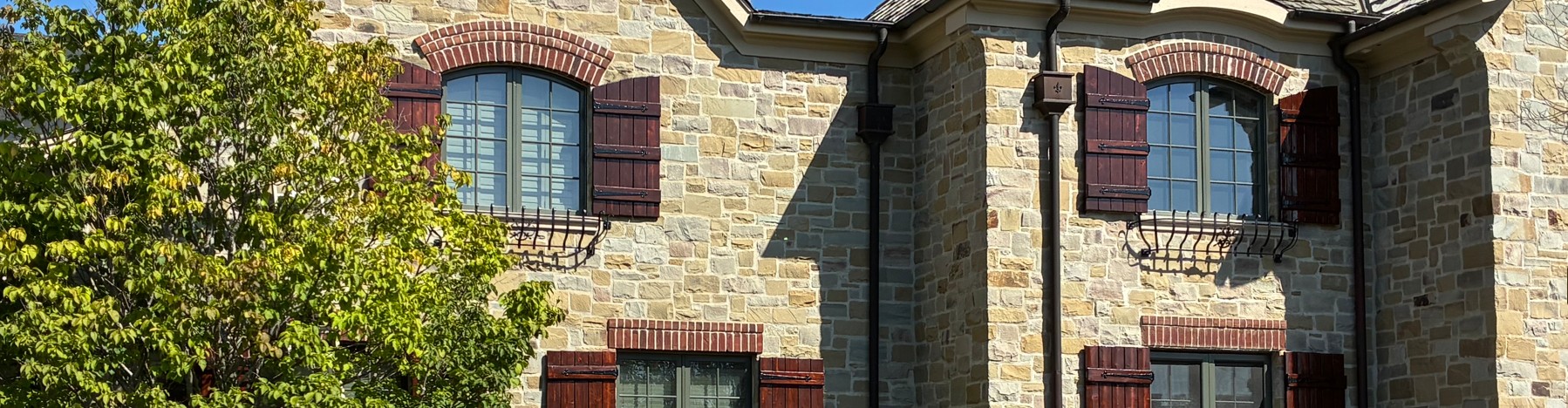 stone house exterior with stained wooden shutters