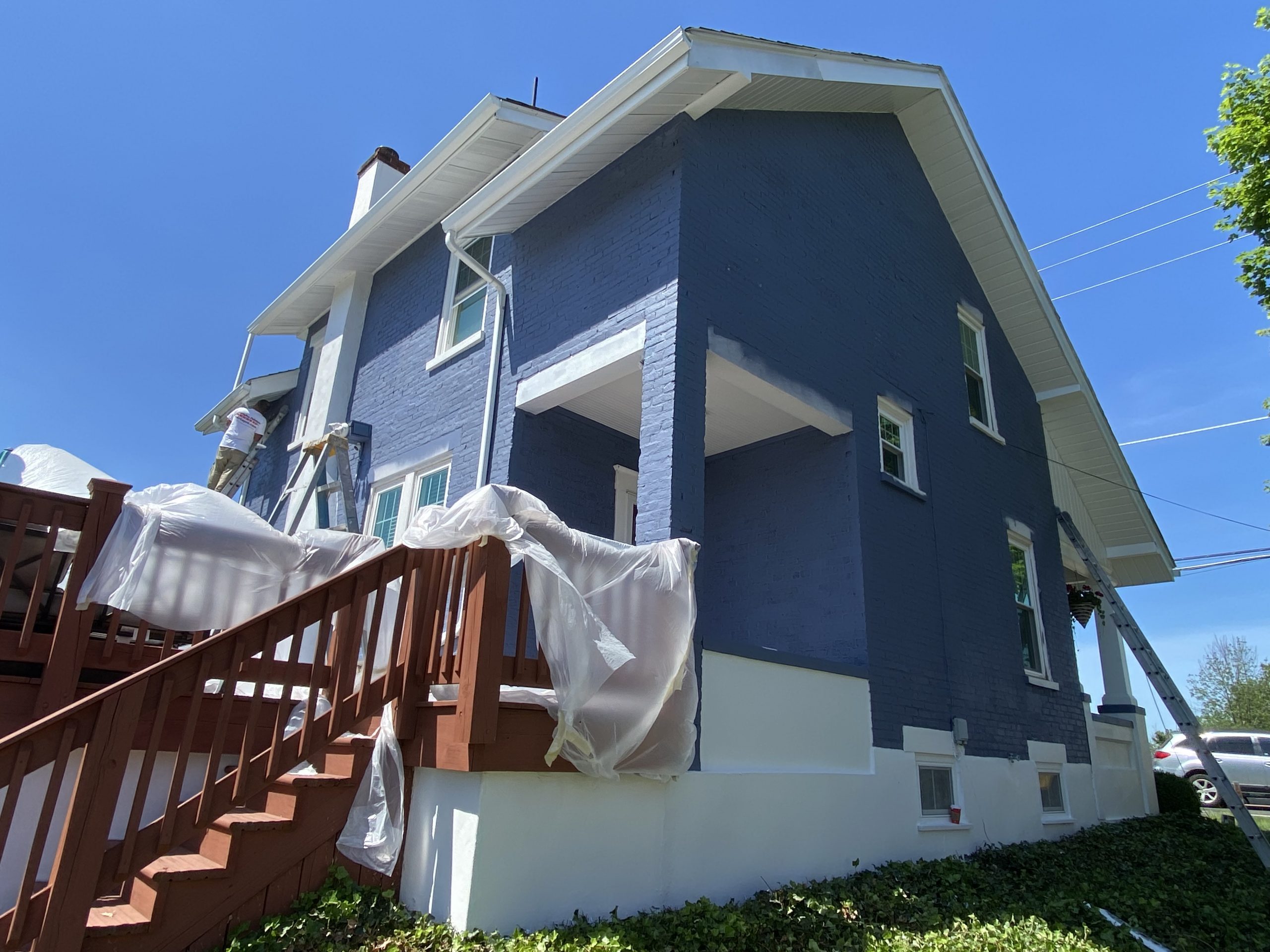 blue painted brick house with white trim and chimney and a brown deck