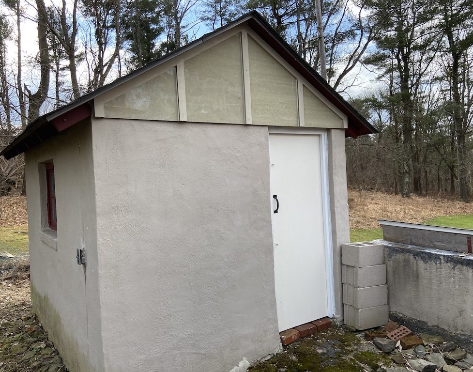 front of tan shed with white door and tan colored wood