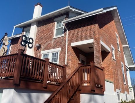 brick house with white trim and chimney and a brown deck