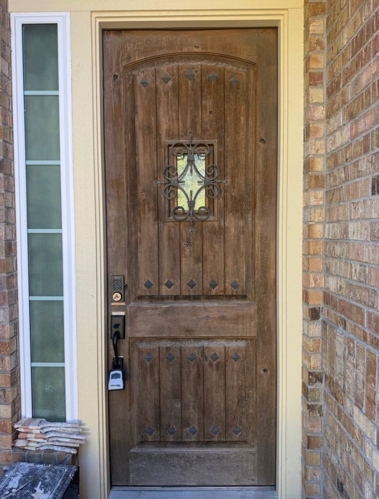 wooden front door with faded and worn stain