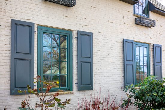 Beige tudor home with green shutters