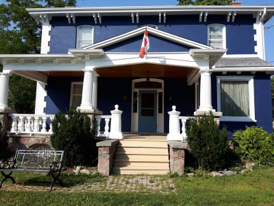 Two-story Dundas home painted deep navy with white porch columns, detailed cornice trim, and a soft blue entry door.