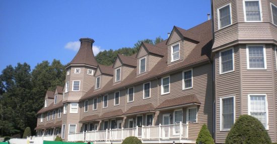 Multi-unit condominium complex in Bedford, MA with taupe painted siding and shingled turrets, white window trim and white balcony railings
