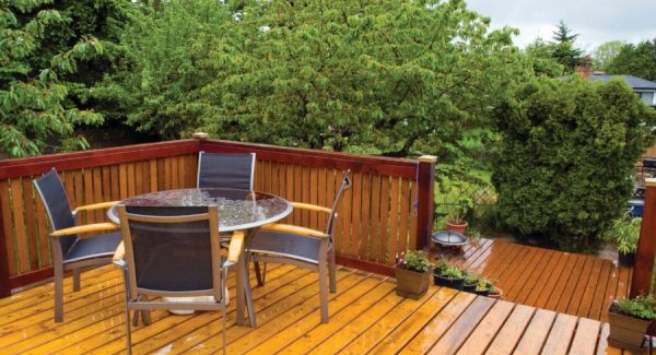 Medicine Hat outdoor wood deck featuring amber-stained floorboards, dark red-brown railings, and a patio dining set.