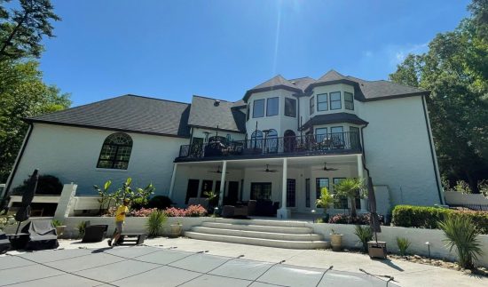 rear side of white painted house with covered patio and steps to inground pool