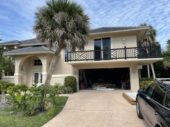 stucco home with balcony above garage door