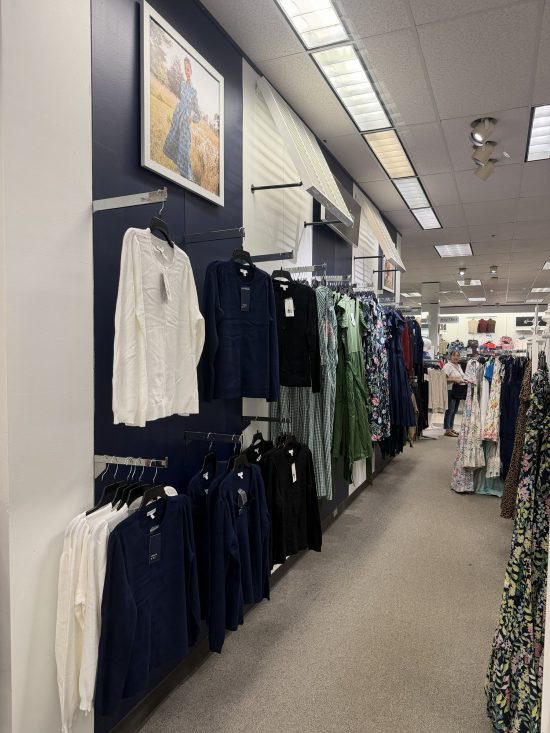 Close view of a navy blue accent wall with white walls and women's sweaters on display after commercial interior painting.