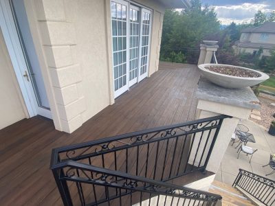 stained wooden deck against house with black metal railing