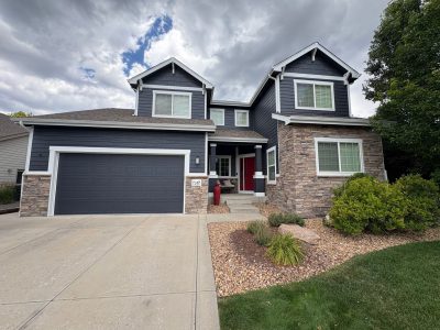 front of house with dark blue siding and garage door