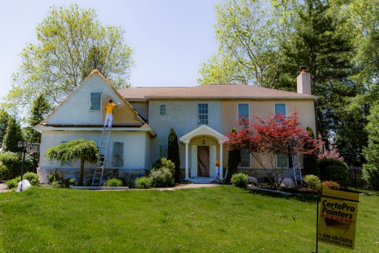 CertaPro Team Member painting stucco home exterior
