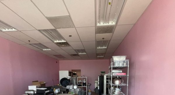 pink painted bakery with equipment stacked in center of room