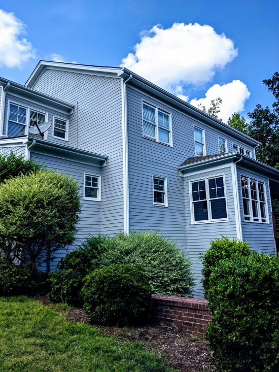 Two-story Tega Cay home featuring cool light blue-gray lap siding, crisp white corner boards, and white roofline trim.