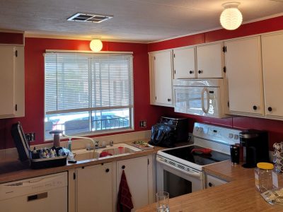 Interior kitchen painting with red walls and white cabinets