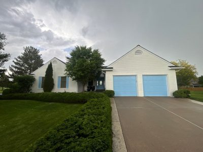 white painted brick home with light blue painted garage doors