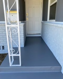 Concrete porch painted medium gray with white wrought iron railing.