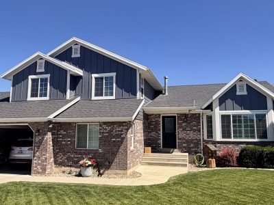 house front exterior with blue painted plank siding, and stonework