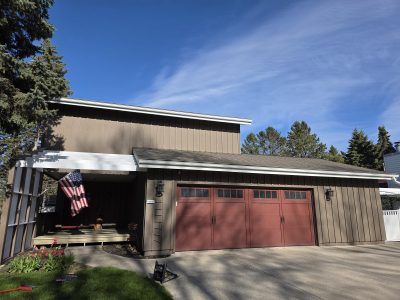 house exterior with brown painted board and batten siding and red garage door