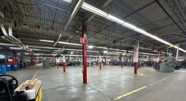 Worn concrete floor and faded yellow safety walkway markings at Apex Tool Group in Dayton, OH before epoxy floor coating.