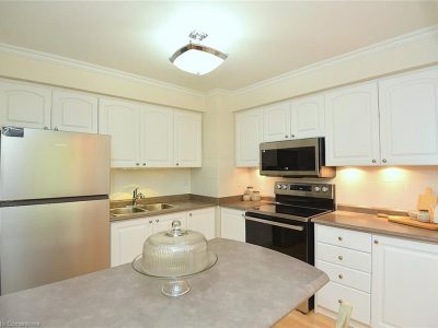 Dundas kitchen featuring refinished white raised-panel cabinets, white crown molding, and stainless steel appliances.