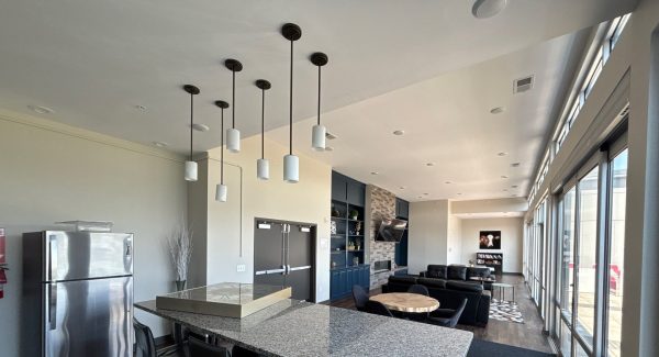 Community kitchen and bar at The Marcum with white cabinetry, stone counters, and pendant lights after painting.