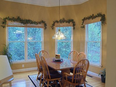 Bright breakfast nook with smooth warm gold walls, white baseboards, and white casings around three tall windows. in Ephrata, PA