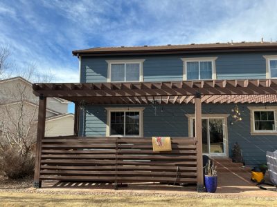 blue house with stained wooden pergola and fence