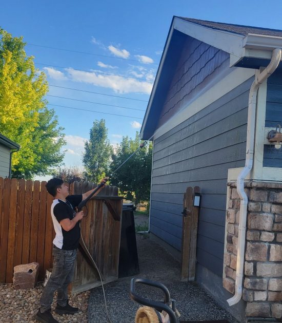 certapro team member power washing house exterior during repaint