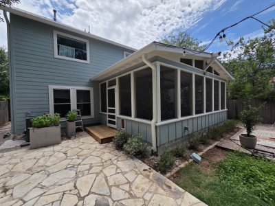 back side of home and sun porch with pale blue siding