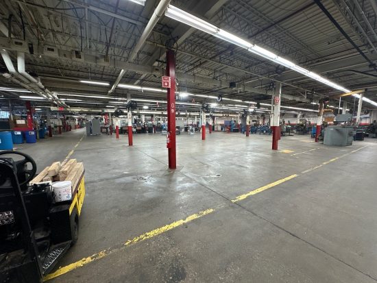 Worn concrete floor and faded yellow safety walkway markings at Apex Tool Group in Dayton, OH before epoxy floor coating.