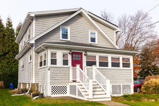 Beige shingled home with white trim and red door
