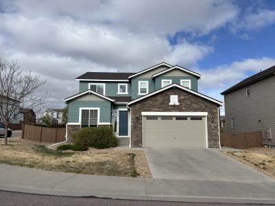 front exterior of house with faux stone and siding painted teal and grey
