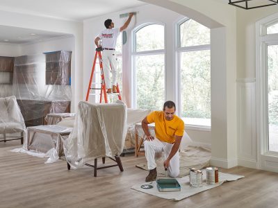 Two men painting the interior of a house