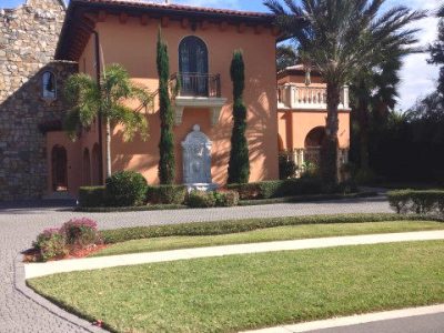 Orlando home displaying warm salmon stucco, dark brown carved corbels, dark window frames, and an unpainted natural stone facade.