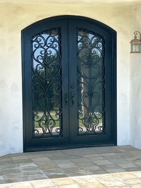 Before photo of arched black wrought-iron front doors on a San Clemente home