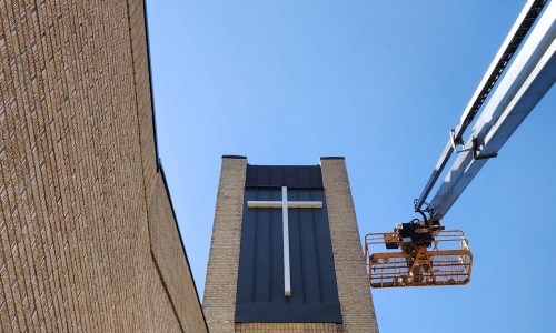 painter on boom lift next to church steeple