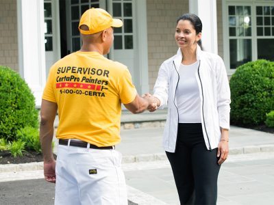 certapro painter and client shaking hands in front of house