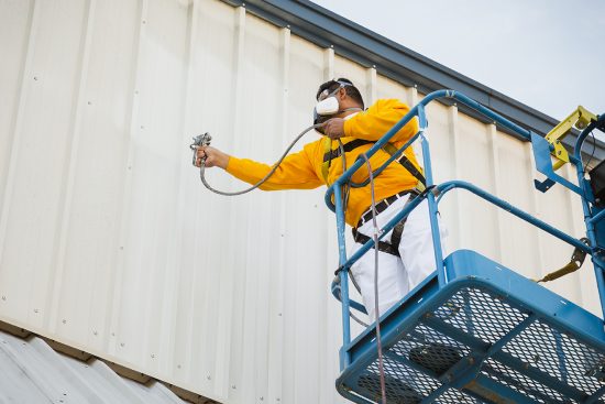 painter painting the outside of a warehouse facility