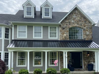 grey house with white trim windows and stone facing after power washing and painting